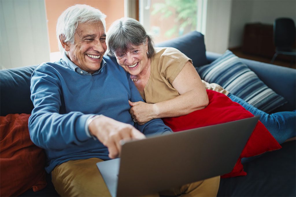 Ein älteres Ehepaar ist glücklich über schnelles Internet am Laptop