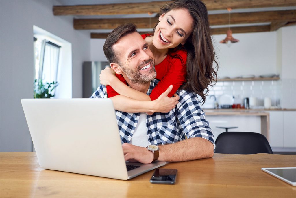 Ein Paar freut sich über schnelles Internet am Laptop in der Küche