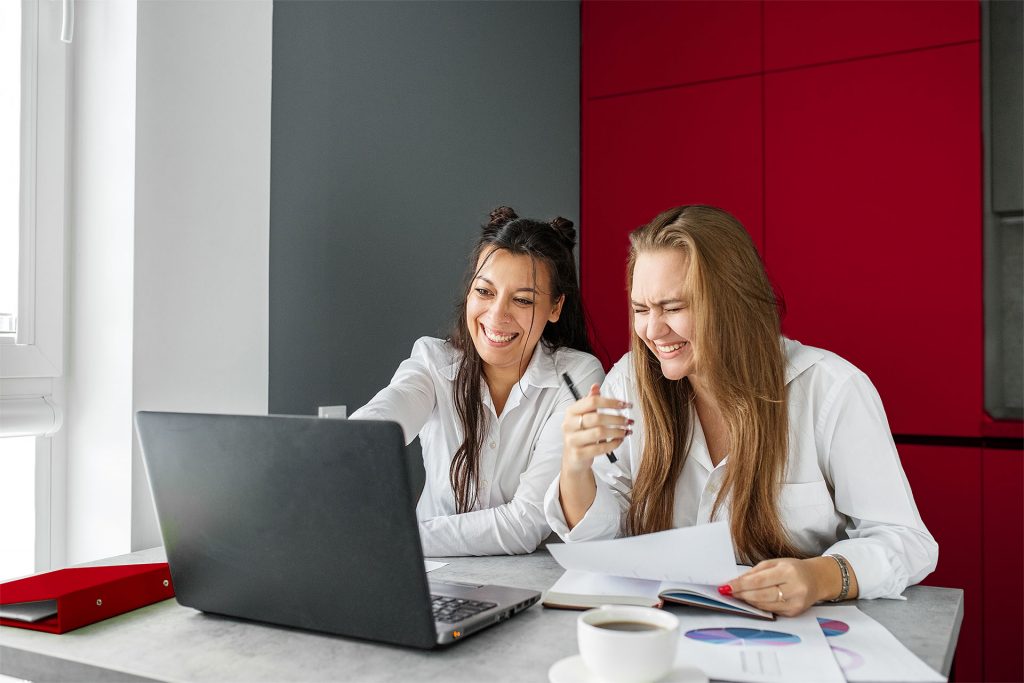 zwei Frauen freuen sich über schnelles Internet am Laptop
