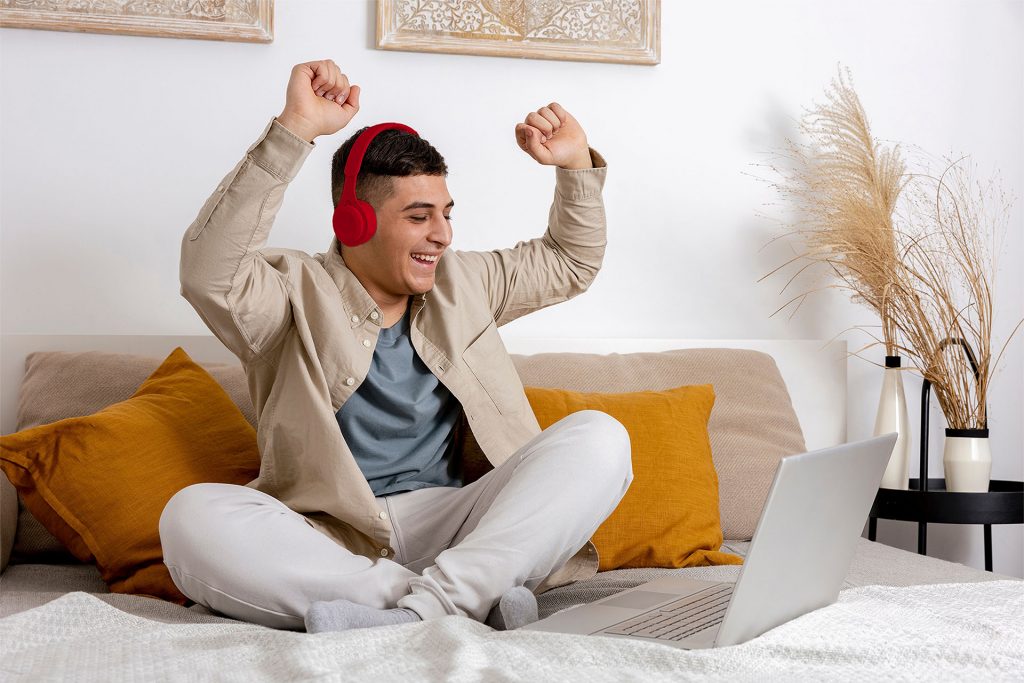 Mann auf dem Bett freut sich über schnelles Internet